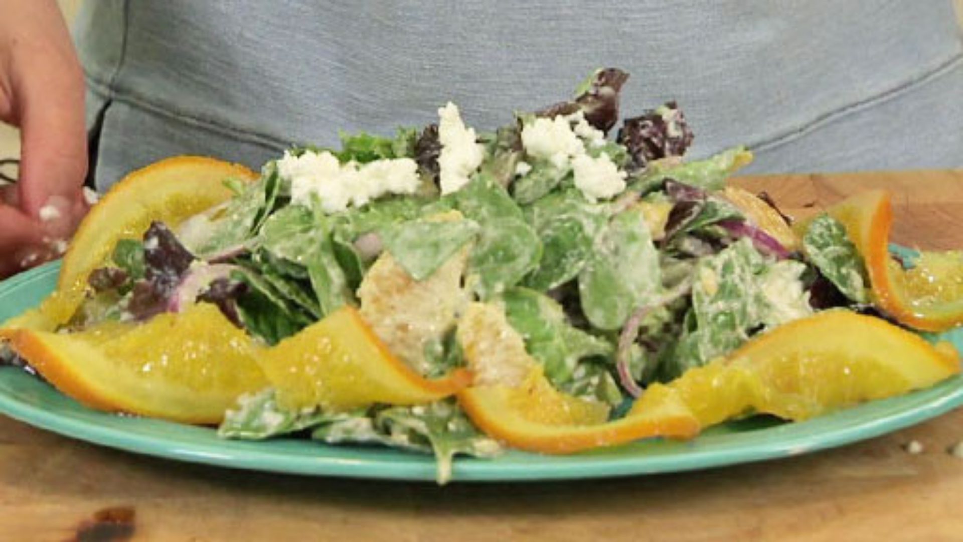 A salad with lettuce, goat cheese, and candied orange slices. 